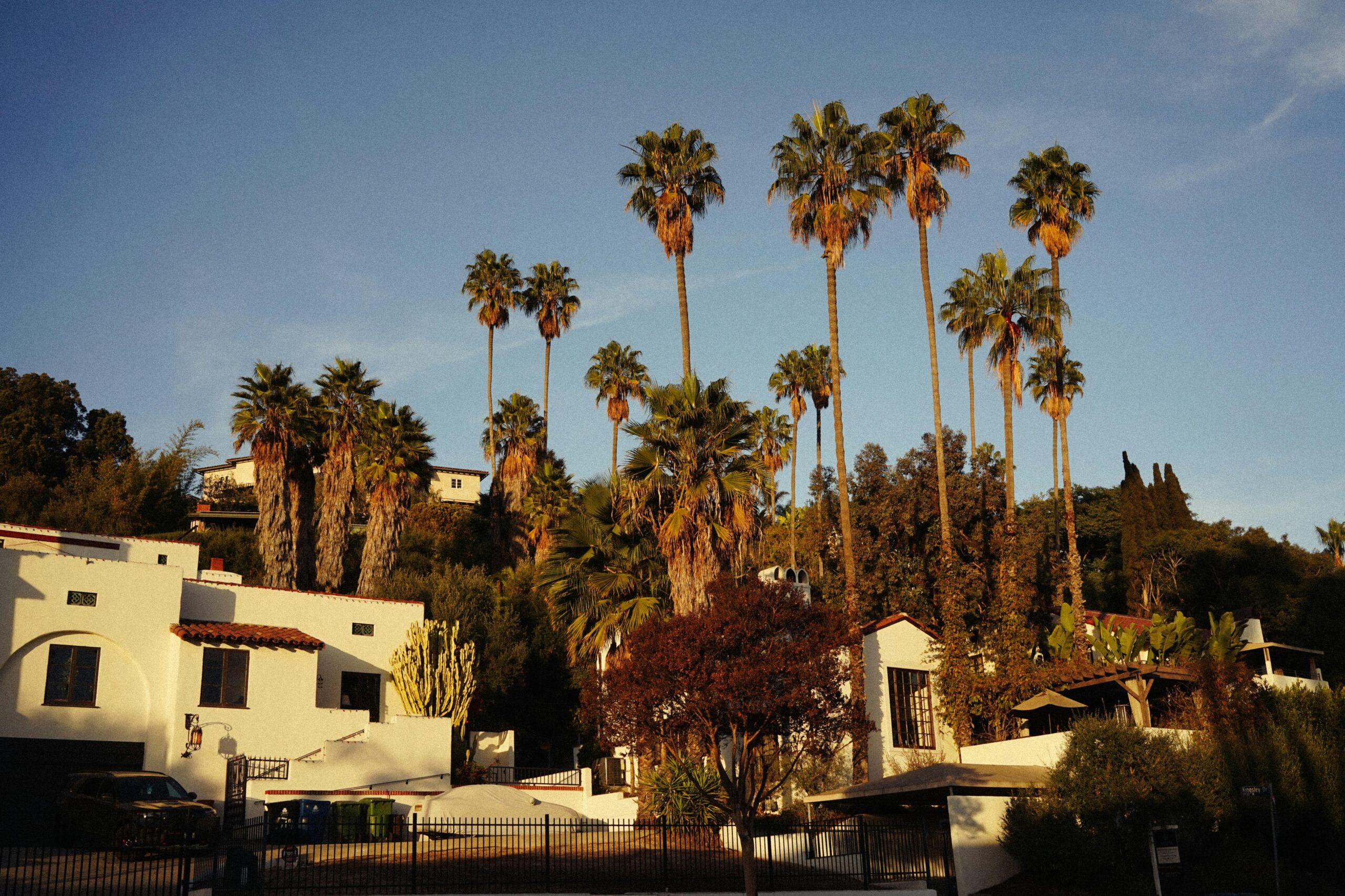 Spanish-style houses with tall palm trees during a warm sunset in Southern California.