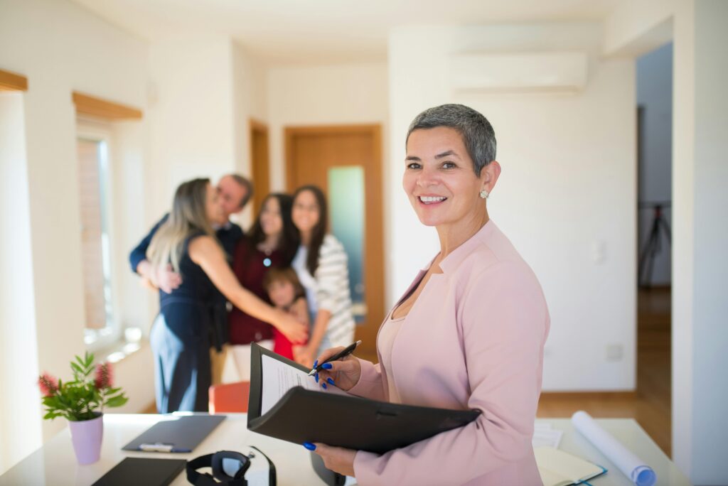 Confident real estate agent presents modern home to elated family, sealing the deal with a smile.